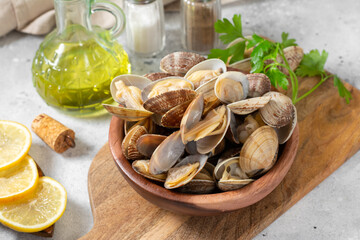 Boiled clams in a wooden bowl on a light gray table. Shellfish close-up. Seafood dish