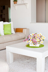 Interior with flowers, home comfort, a table with flowers and a cozy sofa next to it. High quality photo.