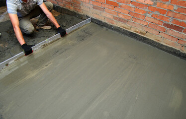 worker screeding indoor cement floor with screed