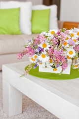 Interior with flowers, home comfort, a table with flowers and a cozy sofa next to it. High quality photo.