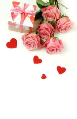 Bouquet of pink roses flowers, gift box  and red hearts confetti isolated  on white background with copy space. Top view. flat lay