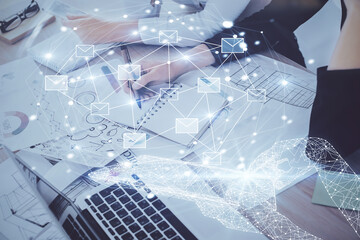 E-mail envelop theme hologram over hands taking notes background. Concept of electronic mail. Double exposure