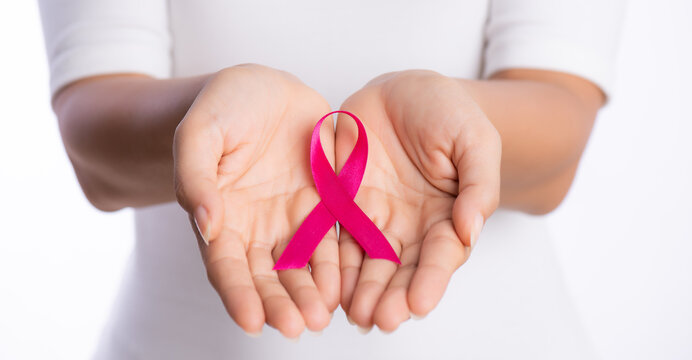 womans hands holding pink breast cancer awareness ribbon on white background. healthcare and medicine concept.