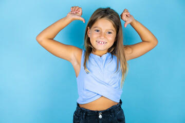 Young beautiful child girl over isolated blue background looking confident with smile on face,...