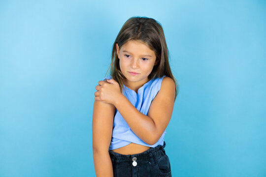 Young Beautiful Child Girl Over Isolated Blue Background With Pain On Her Shoulder And A Painful Expression