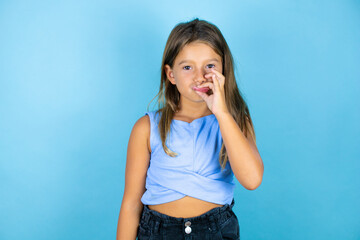 Young beautiful child girl over isolated blue background mouth and lips shut as zip with fingers....