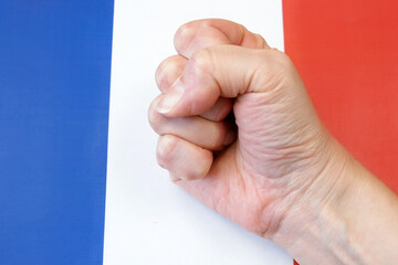 clenched fist against the background of the French flag, protests in France concept