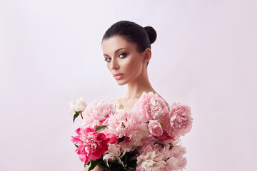 Beautiful woman with pink peony flowers, natural beauty, skin care. Perfect facial features. Girl posing on a light background © angel_nt