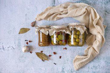 Jars of pickled vegetables on white background, top view. Pickled olives, whole grain mustard,...