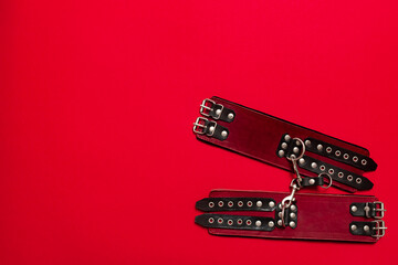 Red color banner with black leather bracers and metal rivets for shackling hands or legs and...