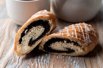 Yeast, soft and fresh poppy roll, sliced in halves,  with a cup of tea