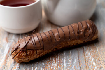 Gourmet chocolate eclair with vanilla custard, close up on wooden table , catalogue photo