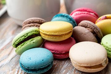 Lots of different macarons on wooden table close up