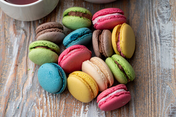 Bright multi colored macarons on wooden background, top view