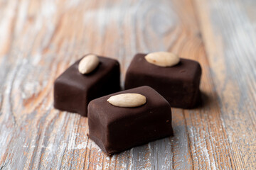 Three small gourmet chocolate candies on wooden background