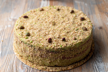 Whole and circle pistachio cake with cookie crumbs on wooden table