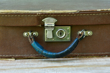  old suitcase lies on a shabby wooden table, front view close-up