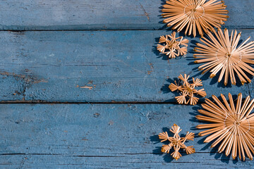 Wooden Christmas background, top view. Place for text on a new year's background. Beautiful blue Christmas background with handmade straw Christmas tree toys and snowflakes.
