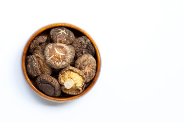 Dried shiitake mushrooms in wooden bowl on white