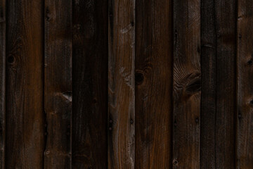Weathered old plank wall in dark grey and yellow tones. Close up.