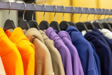 Colorful hoodies on hangers in a sports store close-up