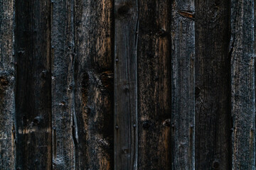 Weathered old plank wall in dark grey and yellow tones. Close up.