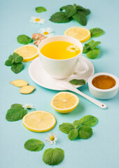 Herbal tea of chamomile flower with mint, ginger, lemon, honey on paper blue background.