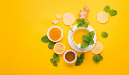 Herbal tea of turmeric with mint, ginger, lemon, honey on paper yellow background.