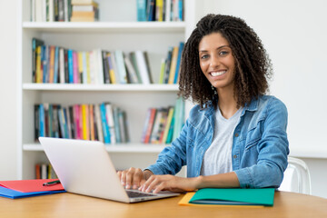 Pretty latin female student learning language online at computer