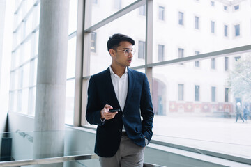 Serious ethnic businessman with smartphone in modern office