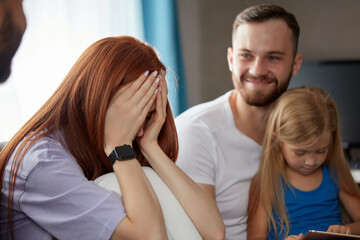 redhead woman suffering from postpartum depression, she came with daughter and husband to get psychological help, she is crying after talks