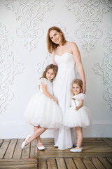 Fototapeta na wymiar mom and daughters in white evening dresses. family celebration. maternal love. mother's day.