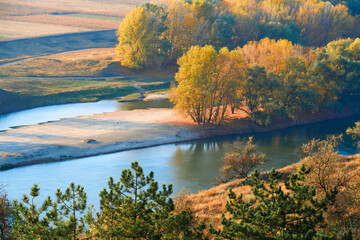 bright colorful autumn forest landscape, trees near river and blue sky, view from high hill