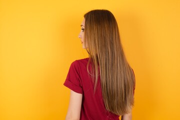 The back side view of a Beautiful Young beautiful caucasian girl wearing red t-shirt over isolated...