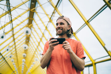 Smiling hipster watching smartphone in city