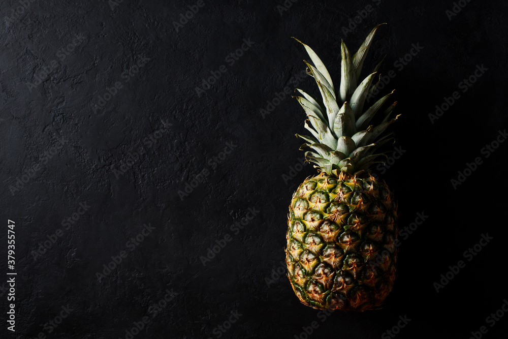 Wall mural Ripe pineapple on a black background