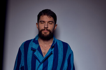 emotional man in a blue striped robe with a belt on a light background cropped view close-up