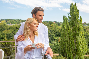 Attractive couple in bathrobe enjoying the view from hotel room terrace