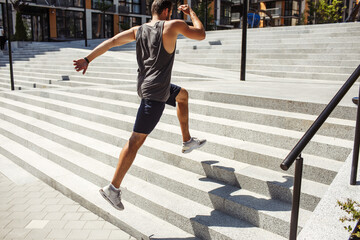 Young man exercising outside. Picture of jumping up process over several steps. Powerful energetic exercise or running. Jumping alone at urban buildings.
