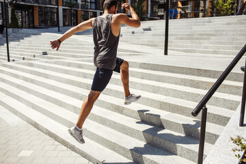 Young man exercising outside. Picture of jumping up process over several steps. Powerful energetic...