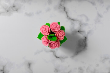 The top view of a toy potted bush of felt roses is on a grey stone  background.  Handmade artificial plants concept. Copy space.