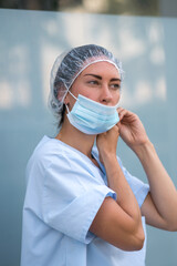 Portrait of a doctor putting on her surgical protective mask