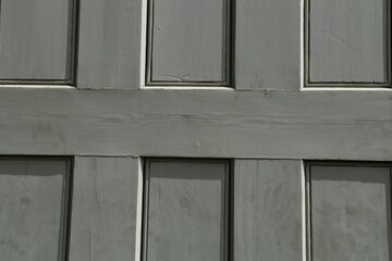 A closeup view of a panel in an old, grey, wooden door.