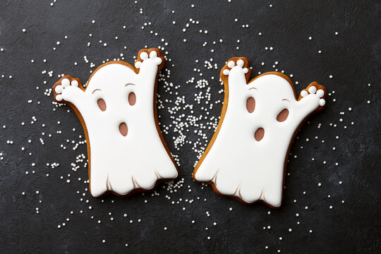 Halloween gingerbread biscuits on black background. Funny white ghosts.
