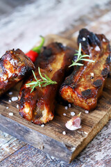 Appetizing grilled pork ribs on a wooden board. Cooking BBQ ribs. Selective focus. Macro.