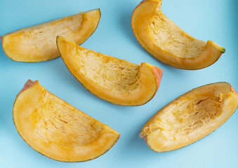 slices of pumpkin on a blue background. Seasonal vegetables, rich harvest, pumpkin cut into pieces. Diet, proper nutrition, healthy vegetables