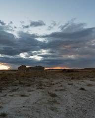 Fototapeta na wymiar atardecer en desierto con nubes del fondo y una casa 