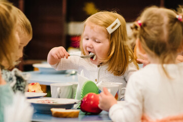 Girl 3 years sits at the table and Independently eating. Kids eat in kindergarten. Lunch.