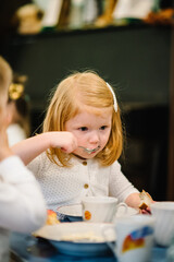 Girl 3 years sits at the table and Independently eating. Kids eat in kindergarten. Lunch.