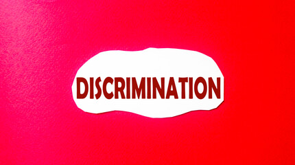 Discrimination written on a scrap of paper and a red background. Abolition of discrimination concept.
